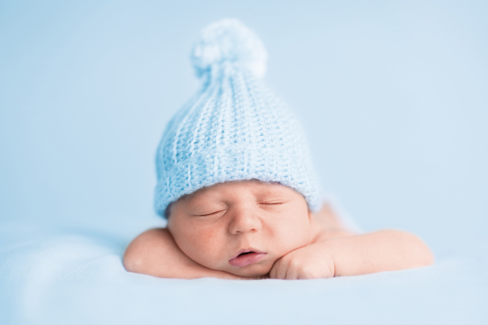 Ein Baby mit hellblauer Pudelmütze, das schläft.