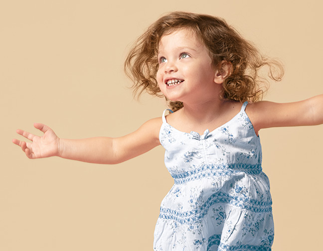 Ein kleines Mädchen breitet glücklich die Arme aus.